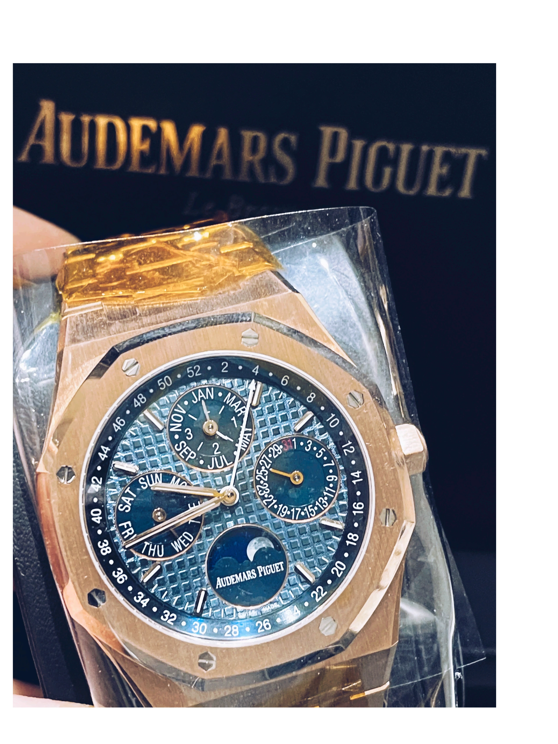Luxury watch with blue face and gold casing, displayed against a dark background with 'Audemars Piguet' branding.